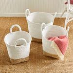 Overhead room view of Madura Market baskets placed on textured rug with a pink throw inside one