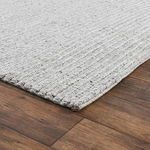 Low angled view highlighting rug's braided texture and soft pile on wood flooring