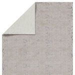 Top corner flipped to reveal cream-colored reverse side of geometric rug