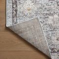 Back side corner of rug lifted to show woven backing texture and edge binding