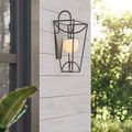 Outdoor wall-mounted sconce glowing softly on light wood horizontal plank wall with plants nearby