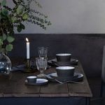 Set of serving dishes including butter dish on rustic wooden table with candle and glassware