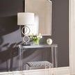Fuller Architectural Arch Mirror mounted on a dark wall above a clear acrylic table with lamp, flowers, and patterned stool