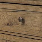 Detailed view of bronzed iron drawer knob on light oak wood front