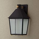 Close-up of seeded glass texture and brass details on Gladden wall sconce against beige background