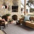Easton Dove Coffee Rug placed outdoors on patio with furniture and stone fireplace background