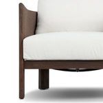 Close-up of chair front corner displaying thick white seat cushion and wooden armrest