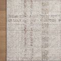 Close-up on corner of rug laying flat on light wood floor, highlighting woven plaid details