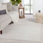 Rug styled in a living room setting with sofa, side table, pouf, and natural light