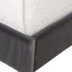Close-up of bottom corner of bed frame showing velvet fabric and natural oak tapered leg