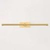 Slim modernist brass picture light with knurled texture along the shade and a rectangular wall mount