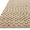 Side angle view showing raised circular cut pile dots on the beige rug surface