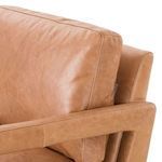 Close-up of chair backrest and arm showing smooth butterscotch leather texture and stitching