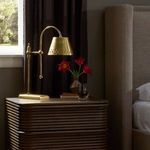 Close-up of perforated brass shade glowing warmly against dark curtain background