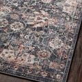 Detailed view of Cassandra rug’s charcoal and rust floral pattern with textured pile on dark floor