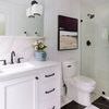 Framed painting hanging on white paneled wall above toilet in contemporary bathroom with black and white tile floor