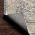 Backside corner folded up to reveal solid grey backing and edge stitching of the rug