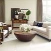 Living room setting with sectional sofa and round dark wood coffee table, striped pillows