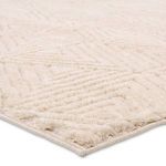 Close-up of the soft plush pile and textured geometric pattern with cream tones on rug corner
