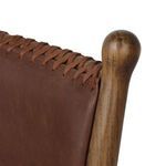 Close-up detail of hand-stitched leather lacing along backrest top and rounded walnut finial