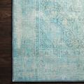 Detail of Loren Aqua Rug corner on dark hardwood floor highlighting muted floral motifs