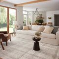 Styled living room scene with rug under sofa and latte neutral décor accents