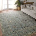 Rug showcased in bright living space with hardwood floor and neutral tufted sofa accented with textured cushions