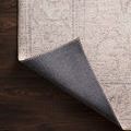 Corner of Loren Sand Rug flipped over to reveal dark woven backing and stitched edge