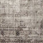 Detail close-up of rug's faded floral motifs and border design in light gray hues