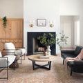 Living room scene with Jules Tangerine / Mist rug anchoring black sofa and white chairs near a fireplace.