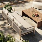 Outdoor patio scene with sofa positioned near wooden low table and surrounded by plants