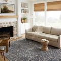 Sorrento Midnight rug styled in bright living room with beige sofa, wooden side tables, and stone fireplace