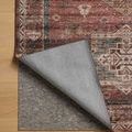 Corner of Anniston Spice Multi rug lifted to show non-slip gray rug pad underneath on wood flooring