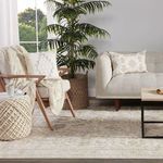 Zoomed perspective of soft rug surface texture combined with woven natural fiber pouf.