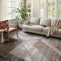 Austen Stone Bark Rug styled in bright living room under soft beige sofa and leather chair