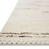 Close-up of rug edge showing stitched border and pile texture from angled side perspective.
