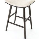 Side angle of stool showing seat curvature and four tapered legs with footrest bars