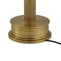 Close-up of vertical grooves and on/off button on polished brass lamp base with black power cord