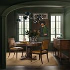 Wide view of green dining room with Archives Leather Chairs, wooden round table, sideboard, and pendant light fixture