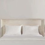 Close-up front view of headboard with white pillows and bedding, showing wood texture