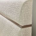 Close-up of textured light caramel fabric upholstery and walnut veneer strip on bed headboard