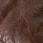 Macro shot of saddle-toned leather showing aged grain and subtle wrinkle texture