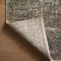 Corner of the rug lifted to reveal the woven backing and edge stitching