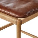 Close-up of leather cushion edge stitching on top of woven seat frame corner