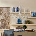 Twiggy Oval Chandelier hanging over a styled desk space with artwork, books, and plants