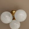 Flush mount with white glass globes viewed directly from below against a beige ceiling