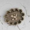 Brown marble tray displayed on cracked white surface holding small seashells