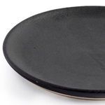 Close-up texture of matte black ceramic salad plate surface revealing subtle natural variations
