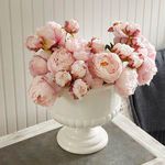 Close-up floral arrangement view of pink peonies overflowing from white pedestal bowl