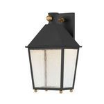 Lantern-style wall sconce in textured black with rippled seeded glass panels and patina brass ball accents